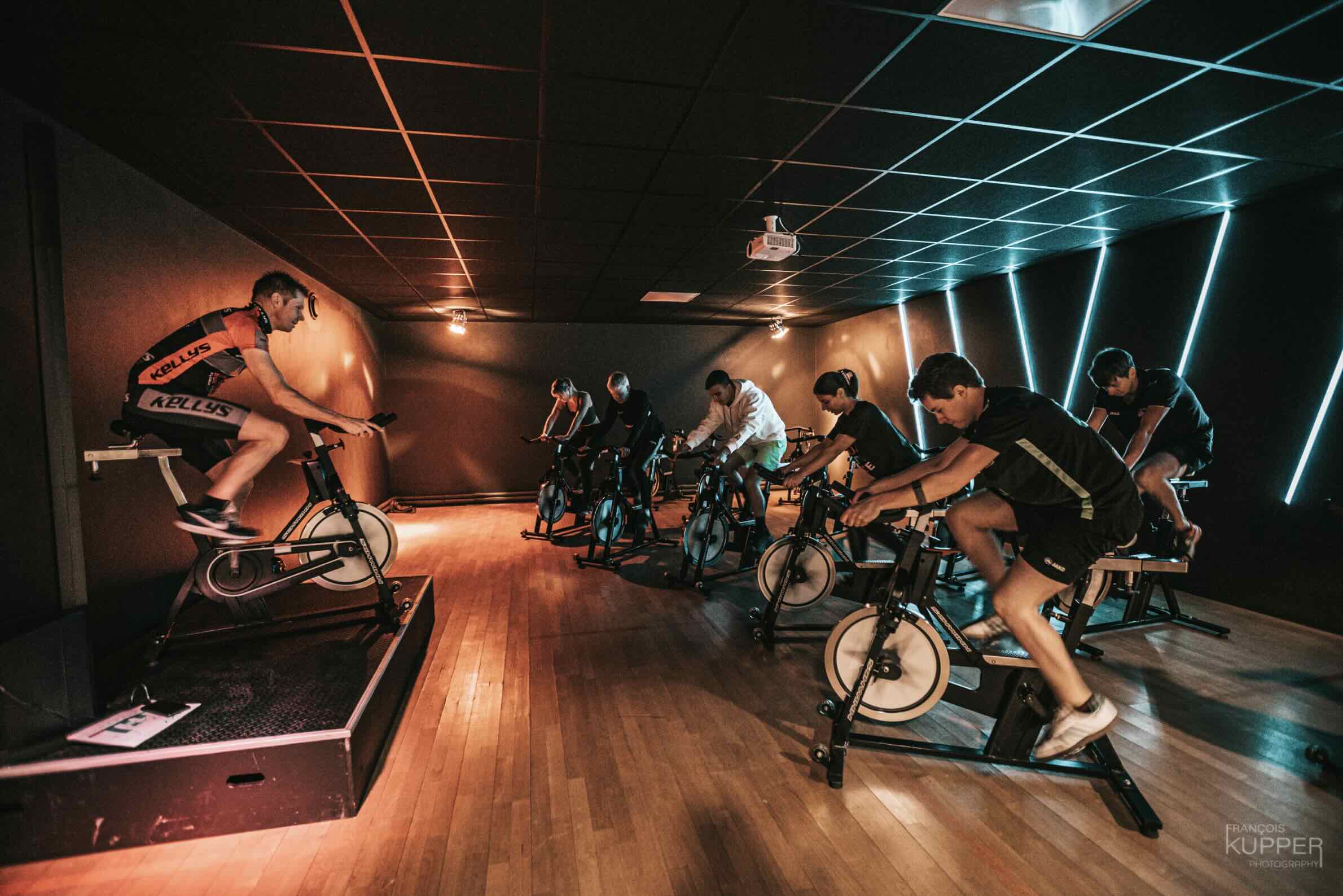 Cours de cycling en groupe dans la salle de sport WAKY Coaching à Malmedy, animé par un coach sur podium